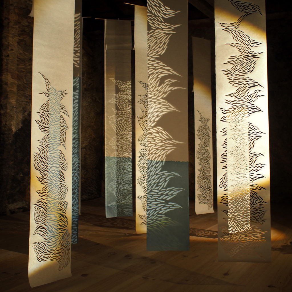 installation théâtre d'ombre faite de kakémonos de papier washi blanc teints en bleus ou incisés suspendus