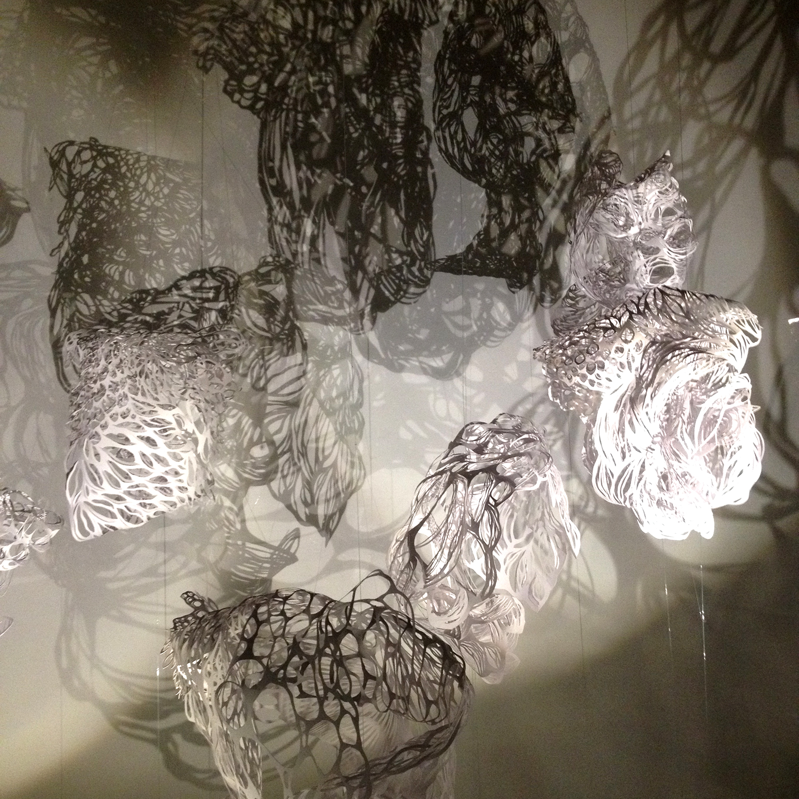 Installation théâtre d'ombres composée de 6 volumes "nuages" en papier découpé tournant sur eux-même