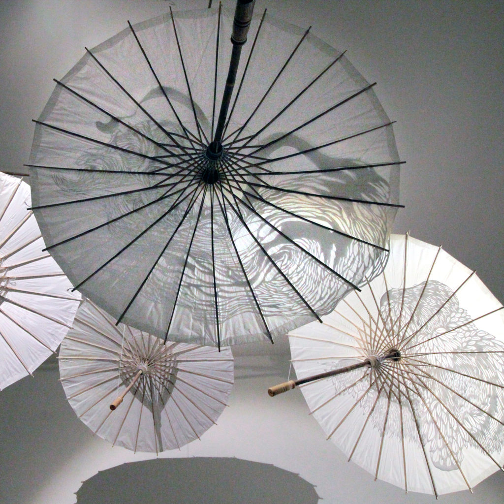 Installation, mobile fait de quatre ombrelles de papier et leurs découpages "aigle", "tigre", "gorille", "dragon"